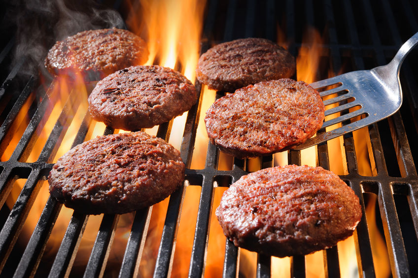 Beef hamburger patties sizzling on the barbecue